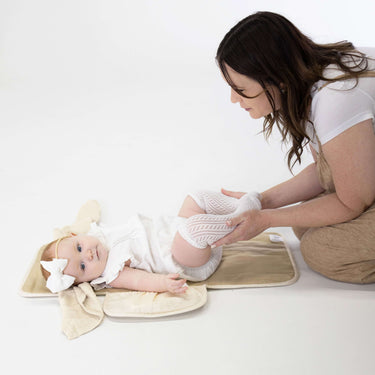 Parent changing baby on toddlekind baby portable changing clutch mini maven tofu opened flat for diapering.