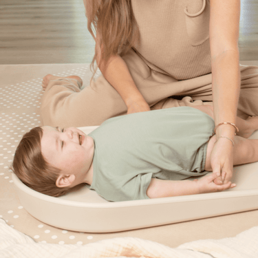 Baby lying comfortably on toddlekind baby foam changing pad nest pad turtle dove during diaper change.