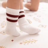 Close-up of baby toddler feet in striped socks standing on the toddlekind baby toddler foam modern designer puzzle play mat haven amira golden clay