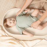 Baby lying comfortably on toddlekind baby foam changing pad nest pad turtle dove during diaper change.