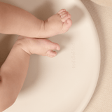 Close-up of baby legs resting on toddlekind baby foam changing pad nest pad turtle dove with smooth curved surface.