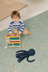 Child playing with an abacus and a toy octopus on a haven mat tulum agave