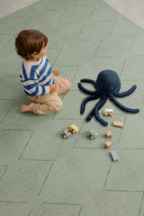 Toddler playing with wooden blocks on the Toddlekind Tulum Agave Playmat, showcasing the cushioned foam play surface.