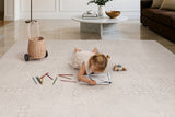 Child drawing on the Toddlekind Aria Playmat with colored pencils, featuring an elegant neutral design perfect for family living spaces.