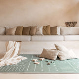 Styled living room scene with pillows, blanket, and toys arranged on toddlekind baby toddler foam modern designer puzzle play mat haven berber moss