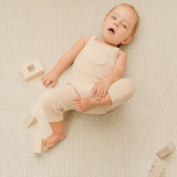 Baby lying and playing with blocks on toddlekind baby toddler foam modern designer puzzle play mat haven deco ecru with soft neutral tones.