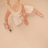 Toddler sitting and playing with a toy car on the toddlekind baby toddler foam modern designer puzzle play mat haven deco latte.