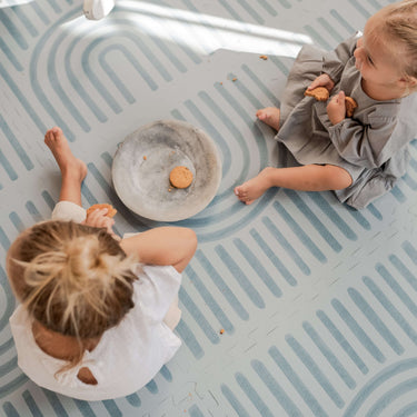 Overhead view of baby and toddler sitting with snacks on the toddlekind baby toddler foam modern designer puzzle play mat haven linear mineral.