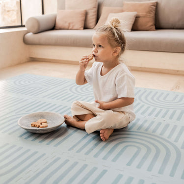 Toddler sitting and eating a snack beside a bowl on the toddlekind baby toddler foam modern designer puzzle play mat haven linear mineral.