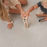 Close-up of hands stacking wooden blocks together on the toddlekind baby toddler foam modern designer puzzle play mat haven tulum stone.