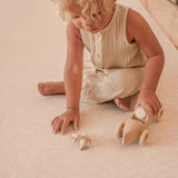 child playing with wooden and cotton toys on toddlekind haven foam puzzle play mat in wild dune