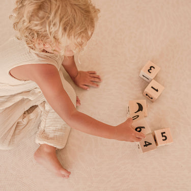 child playing with wooden blocks on toddlekind haven foam puzzle play mat in wild dune