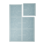 Interlocking tiles arranged in a grid with one piece lifted showing the toddlekind baby toddler foam modern designer puzzle play mat haven linear mineral.