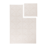 Interlocking tiles arranged in a grid with one piece lifted showing the toddlekind baby toddler foam modern designer puzzle play mat haven tulum bone.