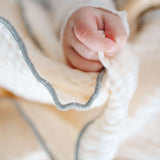 Close-up of toddlekind 3 layer cotton muslin baby blanket kind cloth sage showing breathable texture and stitched edge detail.