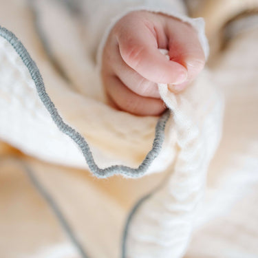Close-up of toddlekind 3 layer cotton muslin baby blanket kind cloth sage showing breathable texture and stitched edge detail.