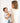Parent holding baby wrapped in toddlekind 3 layer cotton muslin baby blanket kind cloth blush in a soft neutral setting.