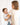 Parent holding baby wrapped in toddlekind 3 layer cotton muslin baby blanket kind cloth blush in a soft neutral setting.