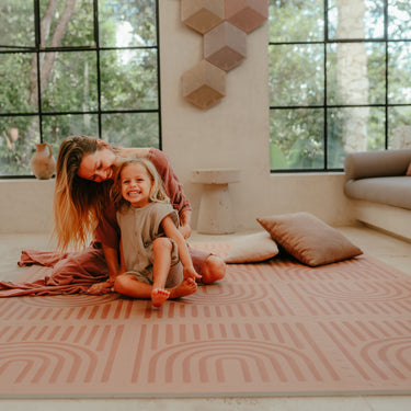 Mother and toddler sitting together smiling on the toddlekind baby toddler foam modern designer puzzle play mat haven linear camel