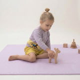 Toddler playing with wooden animal toy on toddlekind baby toddler foam modern puzzle play mat classic lilac.