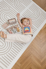 Child lying on the Toddlekind Linear Putty foam playmat showcasing the modern linear pattern.