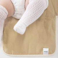 Close-up of baby legs on toddlekind baby portable changing clutch mini maven tofu with soft cushioned surface.