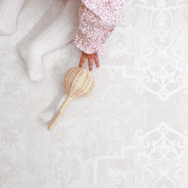 Close-up of toddler hand reaching for a toy on the textured surface of the toddlekind baby toddler foam modern designer puzzle play mat haven parisa millet.