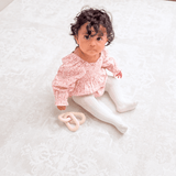 Baby toddler sitting and looking up while playing on the soft surface of the toddlekind baby toddler foam modern designer puzzle play mat haven parisa millet.
