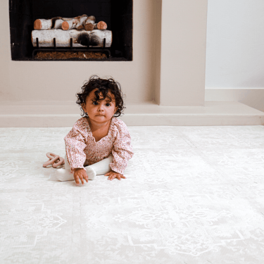 Baby toddler crawling forward on the mat in front of a fireplace, demonstrating use of the toddlekind baby toddler foam modern designer puzzle play mat haven parisa millet.