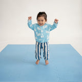 Smiling toddler standing with arms raised on toddlekind baby toddler foam modern puzzle play mat classic slate.