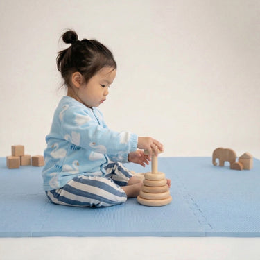 Toddler sitting and stacking wooden rings on toddlekind baby toddler foam modern puzzle play mat classic slate.
