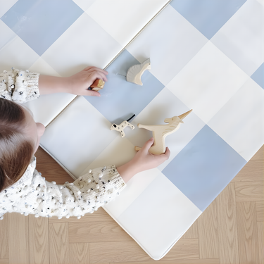 Overhead view of child playing with toys on toddlekind baby toddler foldable foam cushioned tumble play mat arden tide.