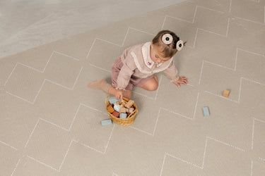 Child playing with toys on a patterned cushioned interlocking playmat