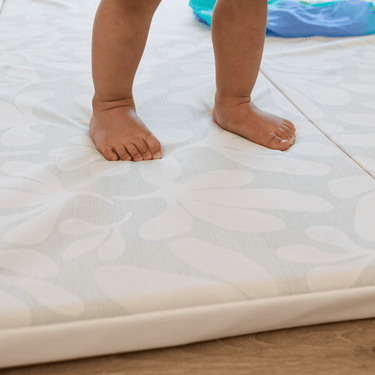 Toddler feet standing on cushioned surface of toddlekind baby toddler foldable foam cushioned tumble play mat willow frost.