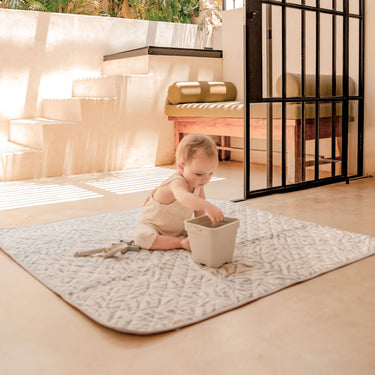 Baby sitting on leaf-pattern play mat outdoors playing with toys – toddlekind portable water resistant wander classic play mat ocean stone for indoor and outdoor play