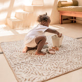 Child kneeling and playing with bucket and molds on soft mat – toddlekind portable water resistant wander classic play mat ocean tan for indoor activities