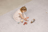 Child playing with wooden toys and a mouse plush toy in the aria maple haven playmat