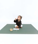 Toddler sitting and drawing on paper on toddlekind baby toddler foam modern puzzle play mat classic moss in minimal setting.