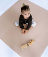 Top view of toddler sitting with wooden toy on toddlekind baby toddler foam modern puzzle play mat classic blush.