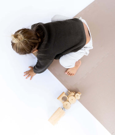 Overhead view of toddler crawling near wooden toy on toddlekind baby toddler foam modern puzzle play mat classic blush.