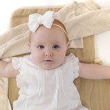 Baby lying on toddlekind baby portable changing clutch mini maven tofu with soft neutral fabric and padding.
