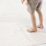 Close-up of child standing barefoot on padded mat texture – toddlekind portable water resistant wander grande play mat tofu for soft supportive flooring
