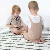 Two toddlers sitting and playing with wooden toy on padded striped mat – toddlekind portable water resistant wander grande play mat forest for shared playtime
