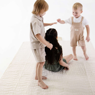 Three children playing together on soft padded mat – toddlekind portable water resistant wander grande play mat tofu for group playtime

