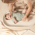 Parent changing baby on toddlekind baby foam changing pad nest pad turtle dove with soft supportive shape.
