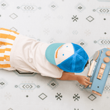 Baby toddler lying on stomach playing with a toy on the toddlekind baby toddler foam modern designer puzzle play mat haven amira seagrass.
