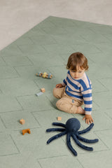 Toddler building with wooden blocks on the Toddlekind Tulum Agave Playmat, showcasing the cushioned foam play surface.