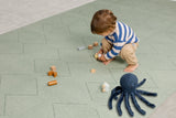 Child  playing on the Toddlekind Tulum Agave Playmat with a modern geometric design.