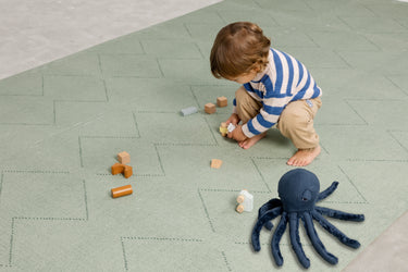 Child  playing on the Toddlekind Tulum Agave Playmat with a modern geometric design.