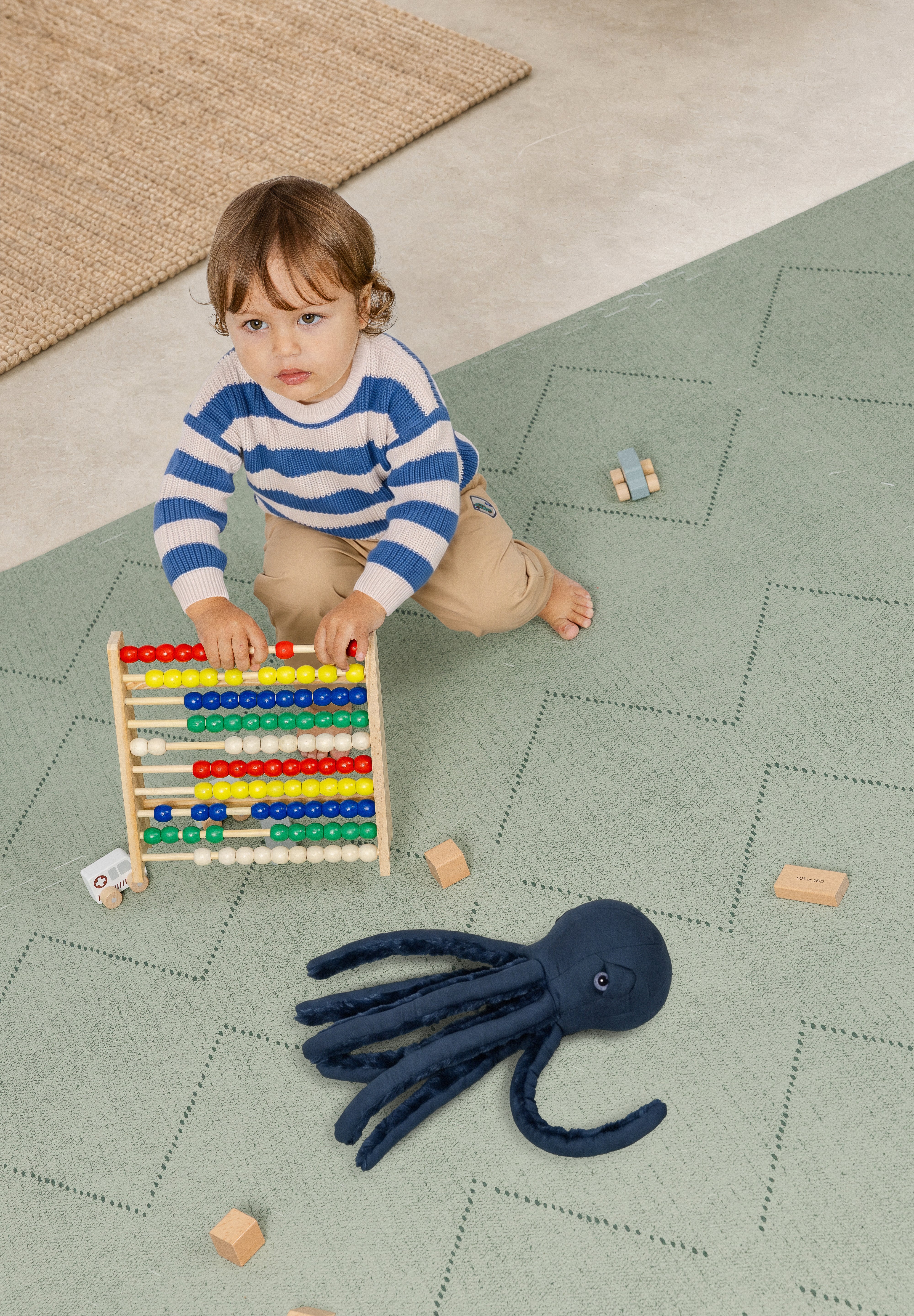 Child playing with an abacus and a toy octopus on a haven mat tulum agave